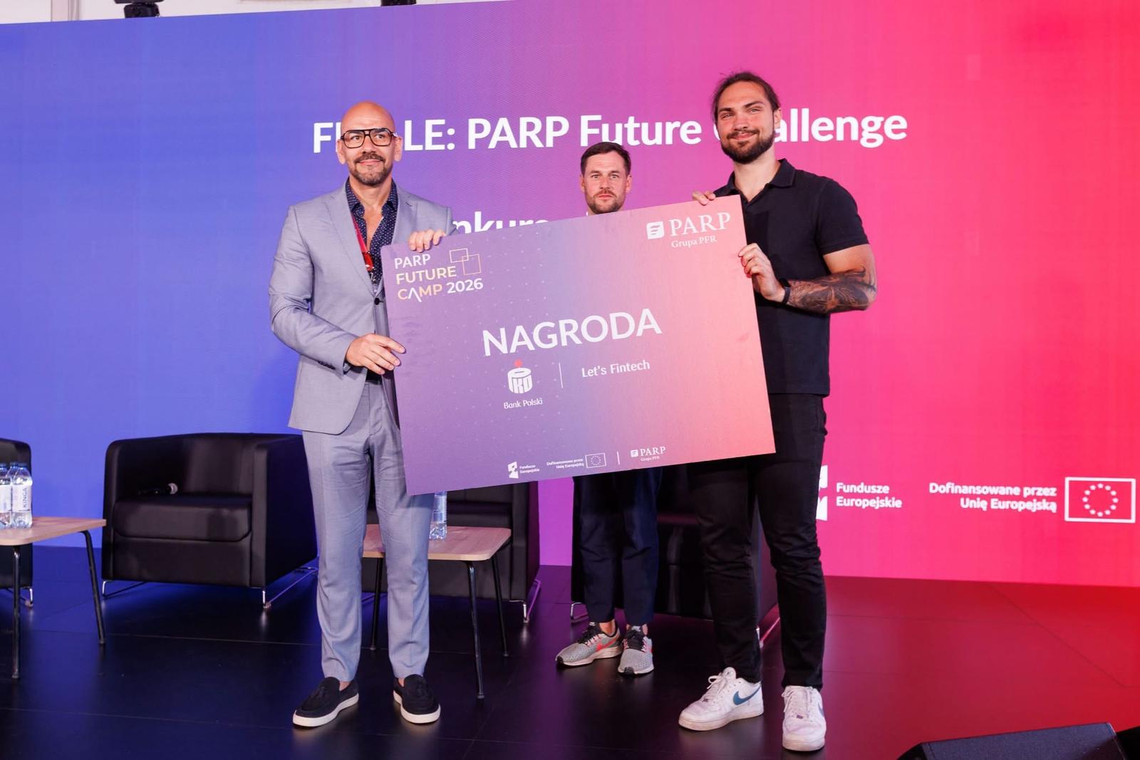 Wręczenie Nagrody PKO Banku Polskiego na finale PARP Future Challenge: trzej mężczyźni trzymają planszę z napisem NAGRODA, PARP Future Camp 2026 i logotypem PKO Banku Polskiego / Let's Fintech.